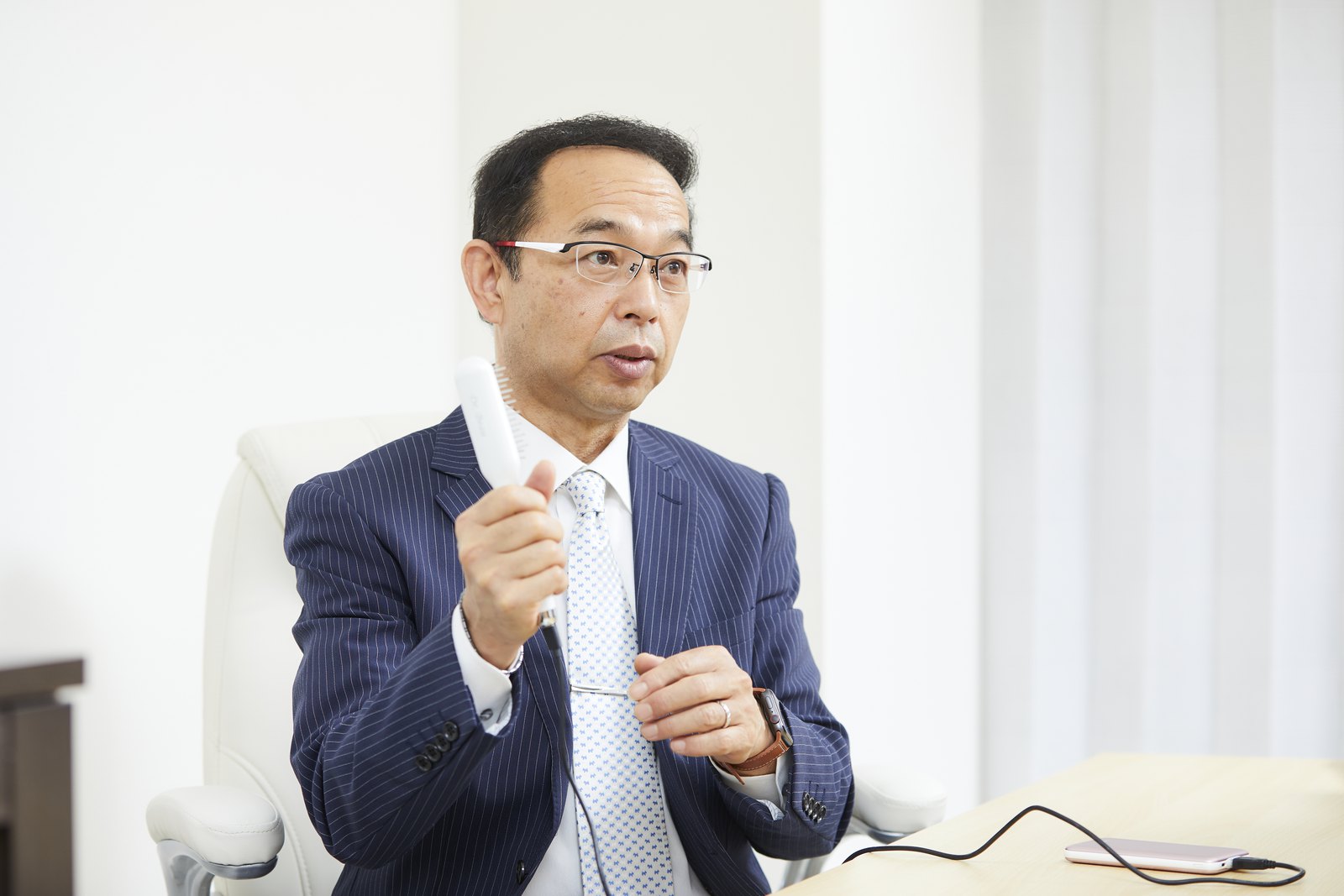 自社開発のヘアケア機器を手に説明する株式会社KALOS BEAUTY TECHNOLOGY 高田栄和社長